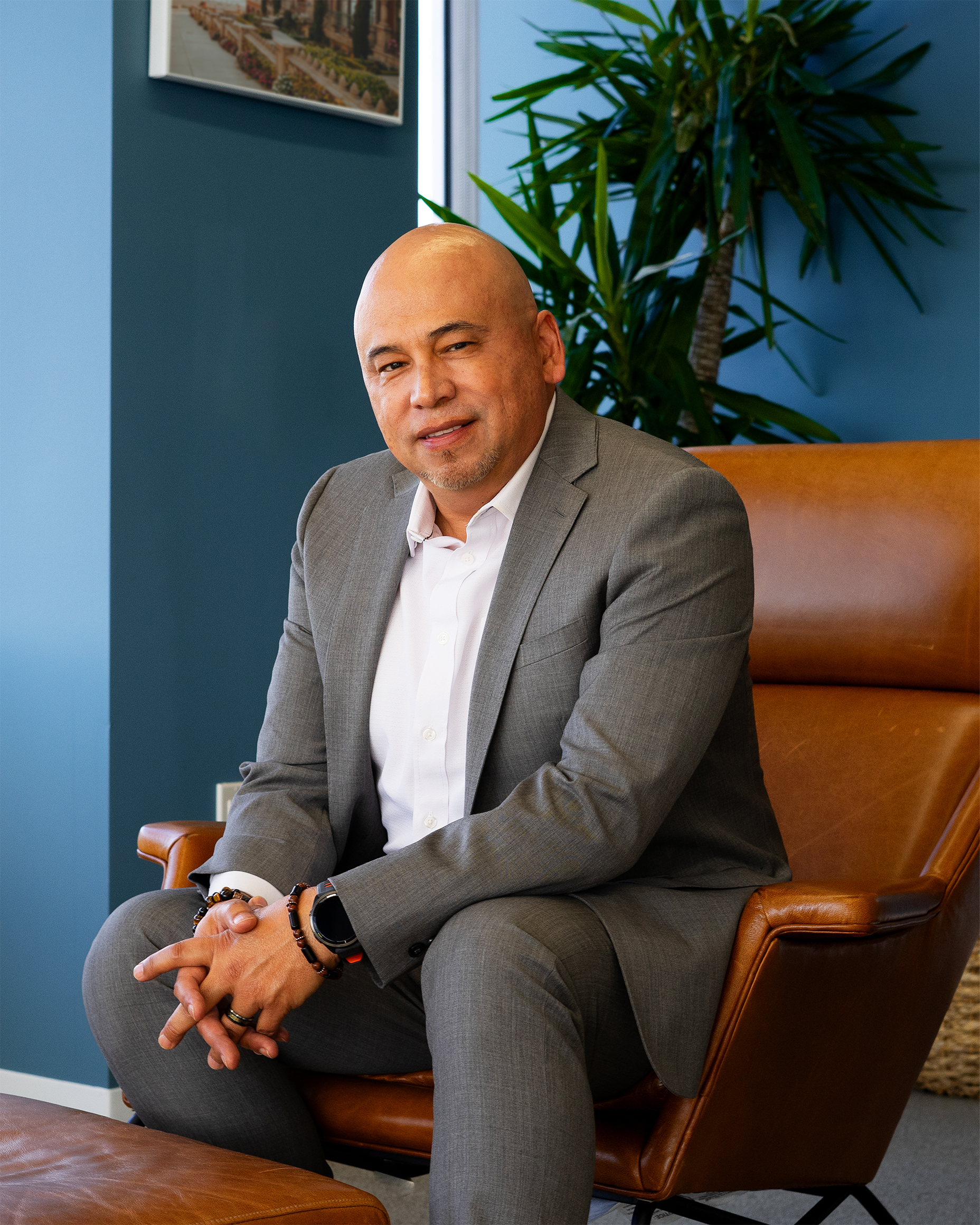 Mynor Arevalo, Regional Sales Manager at BluePoint Mortgage, standing confidently in a gray suit and orange tie, ready to support mortgage brokers nationwide.